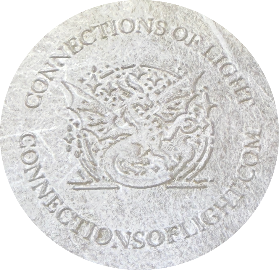 A round, textured surface featuring the embossed text 'CONNECTIONS OF LIGHT' and a decorative emblem in the center.